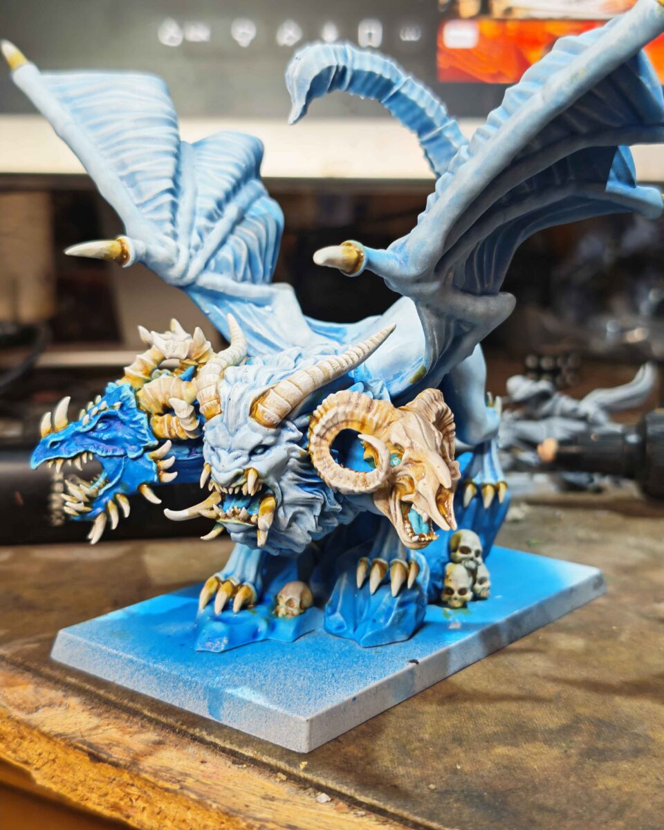 Painted blue and white Chimera with three heads, large wings and an unfinished blue base. Painted blue and white Chimera with three heads, large wings and an unfinished blue base.