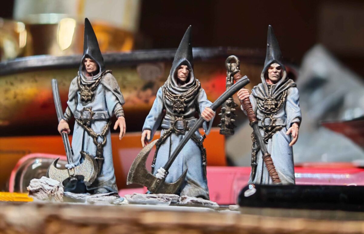 Three painted hooded Cult Magisters in pale grey robes, carrying staffs and standing on unfinished bases Three painted hooded Cult Magisters in pale grey robes, carrying staffs and standing on unfinished bases